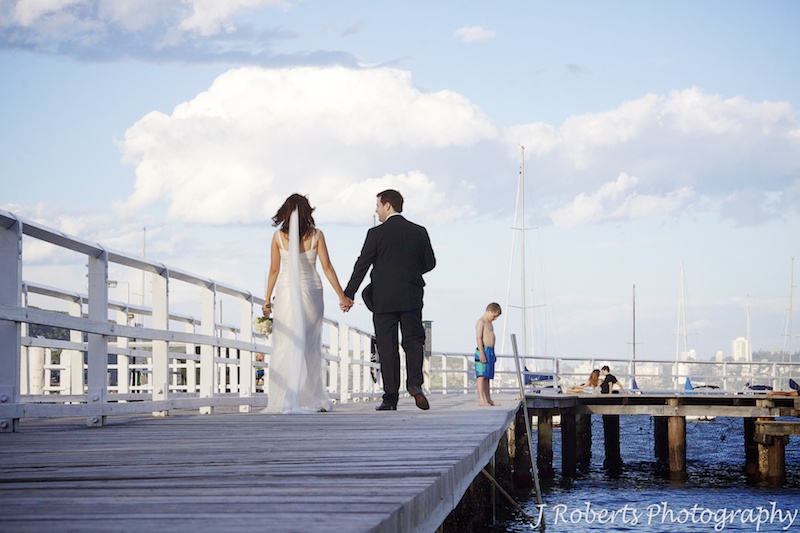 Bride and groom walking along the boardwalk at Balmoral Baths - wedding photography sydney